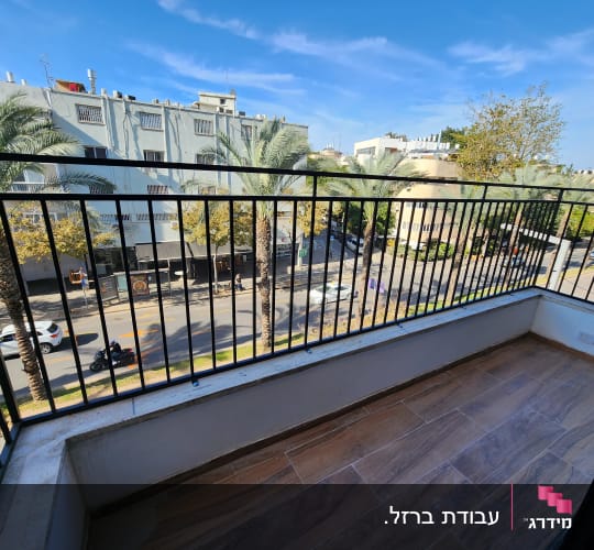 מרפסת עם רצפת עץ ומעקה מתכת שחור